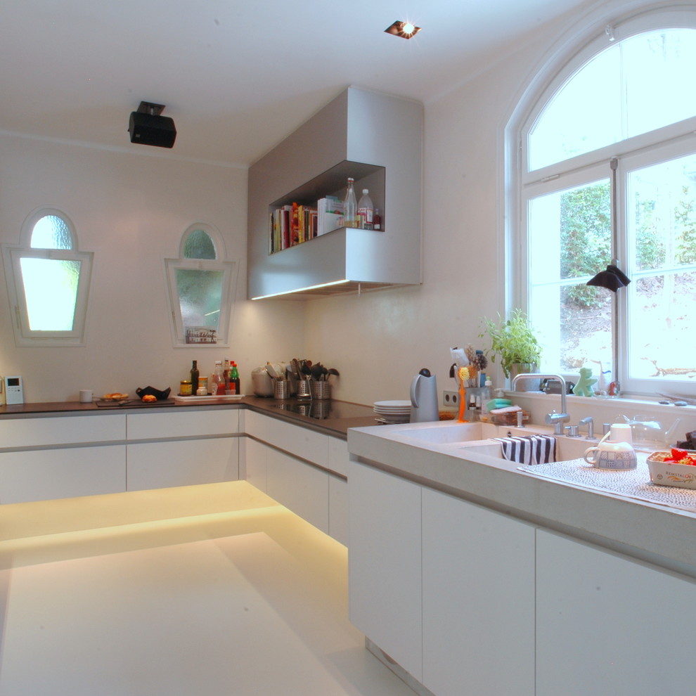 Geschlossene Moderne Küche ohne Insel in U-Form mit weißen Schränken, Küchenrückwand in Weiß und Küchengeräten aus Edelstahl in Stuttgart