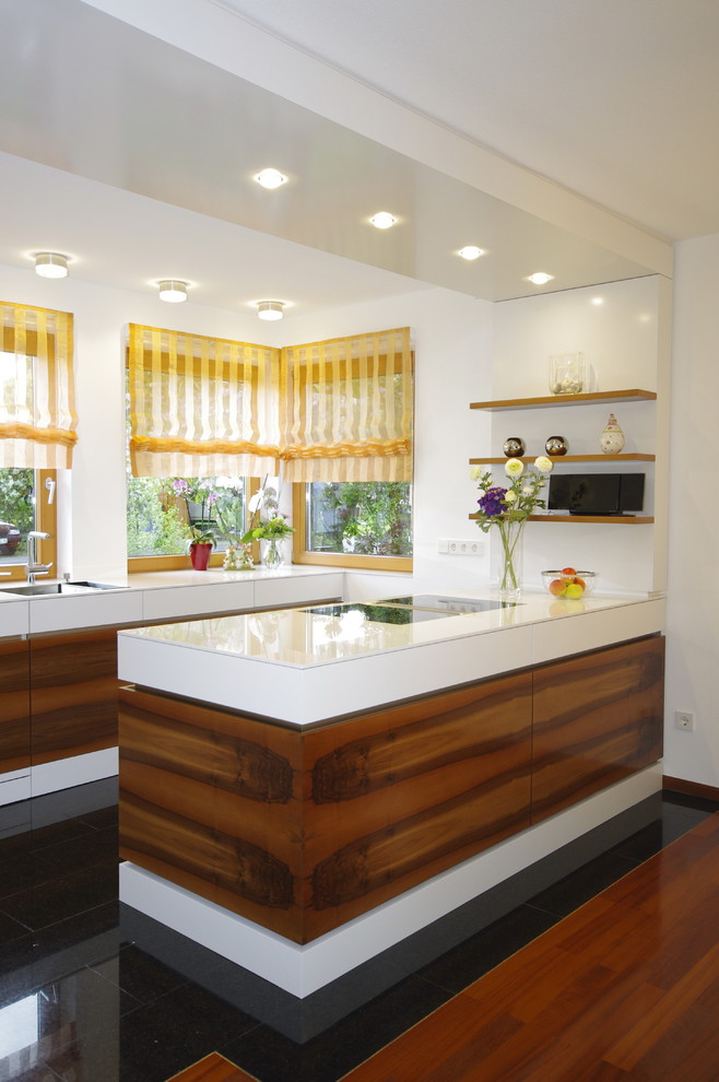 Foto på ett mellanstort funkis vit kök, med en nedsänkt diskho, släta luckor, skåp i mörkt trä, bänkskiva i glas, en halv köksö, svart golv, vitt stänkskydd, rostfria vitvaror och klinkergolv i porslin