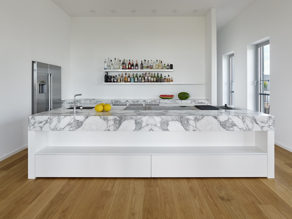 Offene, Zweizeilige Moderne Küche mit integriertem Waschbecken, weißen Schränken, Marmor-Arbeitsplatte, Küchengeräten aus Edelstahl, braunem Holzboden und Kücheninsel in Frankfurt am Main