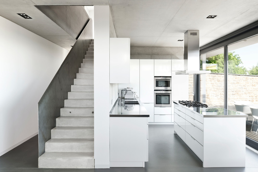 Пример оригинального дизайна: отдельная, угловая кухня среднего размера в стиле модернизм с плоскими фасадами, белыми фасадами, столешницей из нержавеющей стали, островом, двойной мойкой и техникой из нержавеющей стали