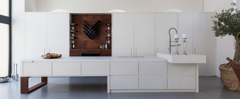 Imagen de cocina moderna abierta con armarios con paneles lisos, puertas de armario blancas, suelo de cemento, una isla, fregadero encastrado y encimera de acrílico