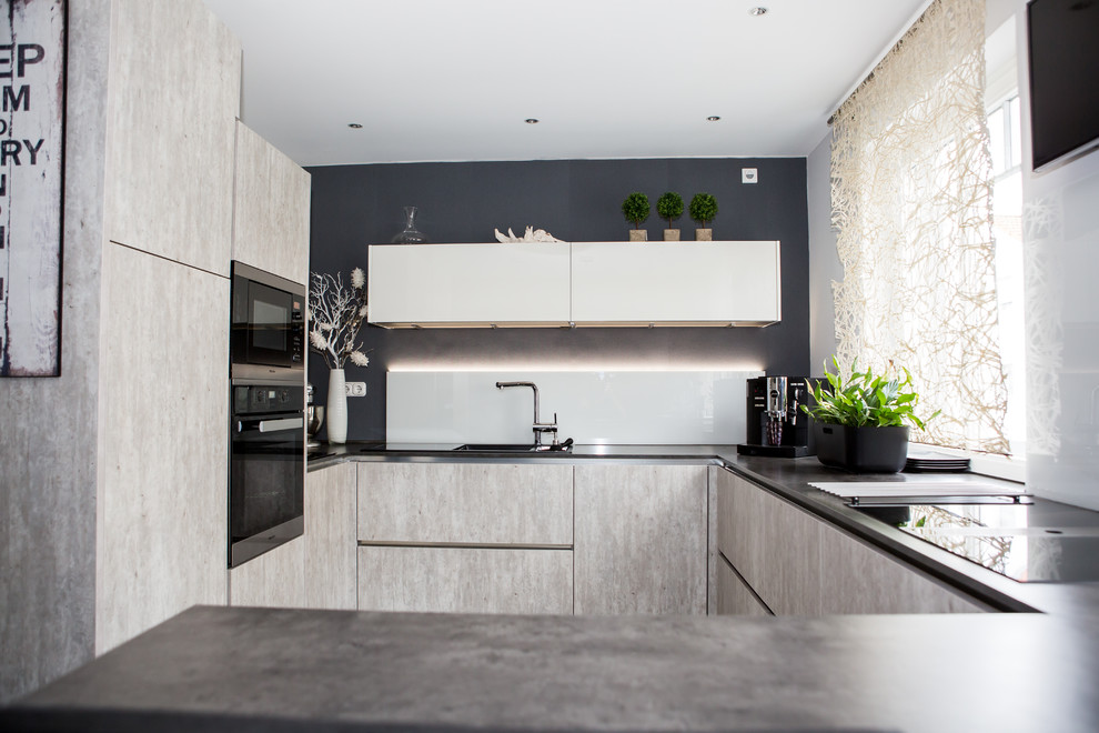 Idee per una piccola cucina design con lavello da incasso, ante lisce, ante beige, elettrodomestici neri, pavimento in cementine e pavimento grigio