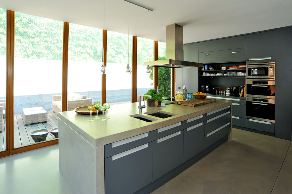 Medium sized contemporary enclosed kitchen in Frankfurt with a double-bowl sink, flat-panel cabinets, grey cabinets, concrete worktops, stainless steel appliances, concrete flooring and an island.
