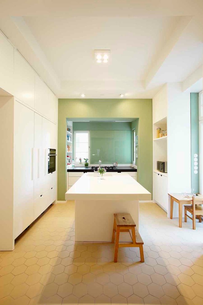 Свежая идея для дизайна: огромная отдельная кухня в современном стиле с плоскими фасадами, белыми фасадами, зеленым фартуком, островом, одинарной мойкой и черной техникой - отличное фото интерьера