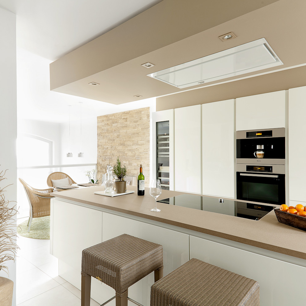 Modern inredning av ett mellanstort kök med öppen planlösning, med släta luckor, vita skåp, integrerade vitvaror och en köksö