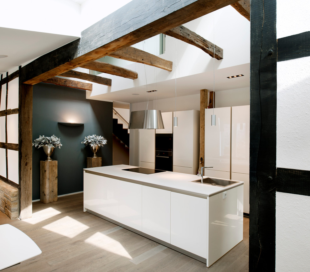 Exempel på ett stort modernt kök med öppen planlösning, med en nedsänkt diskho, släta luckor, vita skåp, svarta vitvaror, mellanmörkt trägolv och en köksö
