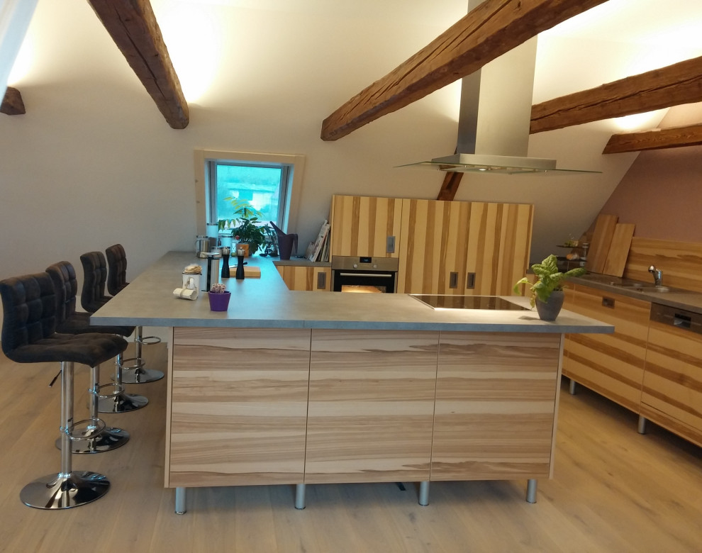 Photo of a large contemporary u-shaped kitchen/diner in Dresden with flat-panel cabinets, laminate countertops, stainless steel appliances and a breakfast bar.