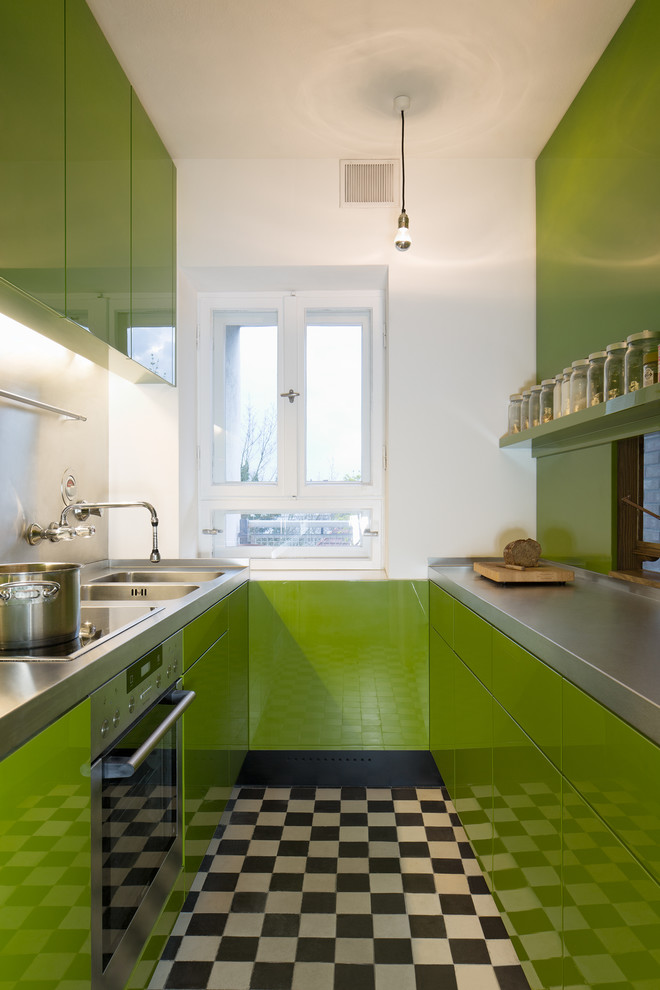 ケルンにある小さなコンテンポラリースタイルのおしゃれなキッチン (フラットパネル扉のキャビネット、緑のキャビネット、ステンレスカウンター、ダブルシンク、メタリックのキッチンパネル、シルバーの調理設備、アイランドなし) の写真