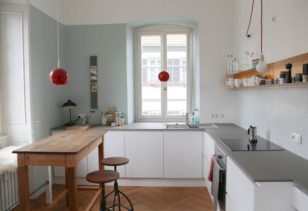 Exempel på ett avskilt, litet minimalistiskt l-kök, med en nedsänkt diskho, släta luckor, vita skåp, stänkskydd i mosaik, rostfria vitvaror, ljust trägolv, bänkskiva i koppar och grått stänkskydd