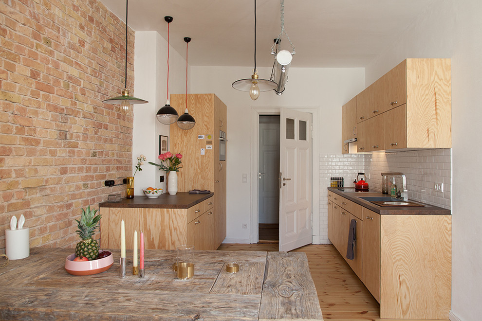 Example of a mid-sized eclectic galley light wood floor and brown floor eat-in kitchen design in Berlin with a drop-in sink, flat-panel cabinets, brown cabinets, white backsplash, stainless steel appliances and no island