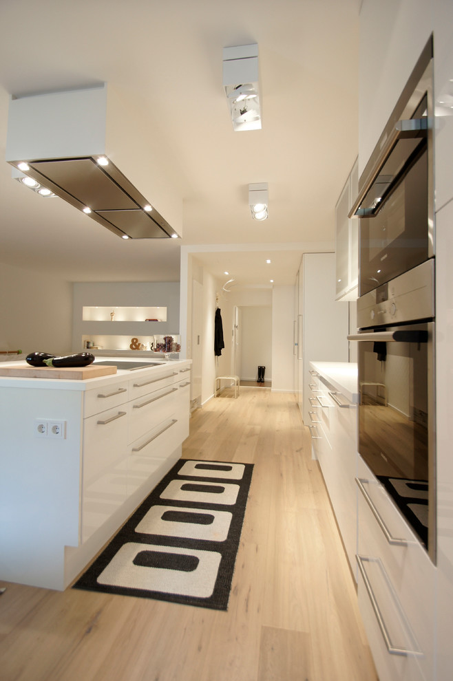 Idées déco pour une cuisine contemporaine de taille moyenne avec des portes de placard blanches, un plan de travail en surface solide, îlot et un plan de travail blanc.