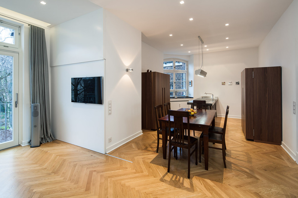 Mittelgroße Moderne Wohnküche mit flächenbündigen Schrankfronten, dunklen Holzschränken, braunem Holzboden und Halbinsel in Düsseldorf