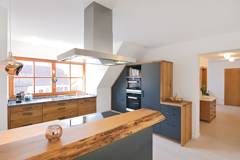 Inredning av ett modernt stort grå grått kök, med en integrerad diskho, släta luckor, marmorbänkskiva, stänkskydd i trä, rostfria vitvaror, ljust trägolv och en köksö