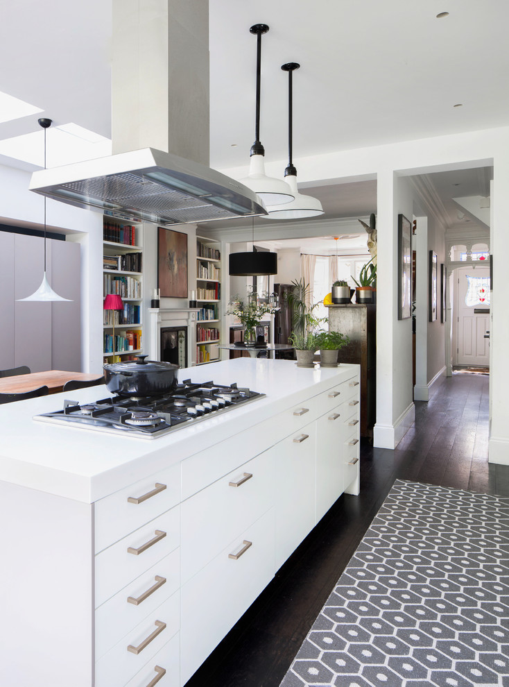 Design ideas for a medium sized contemporary galley open plan kitchen in London with flat-panel cabinets, white cabinets, dark hardwood flooring, an island, black floors, white worktops and engineered stone countertops.
