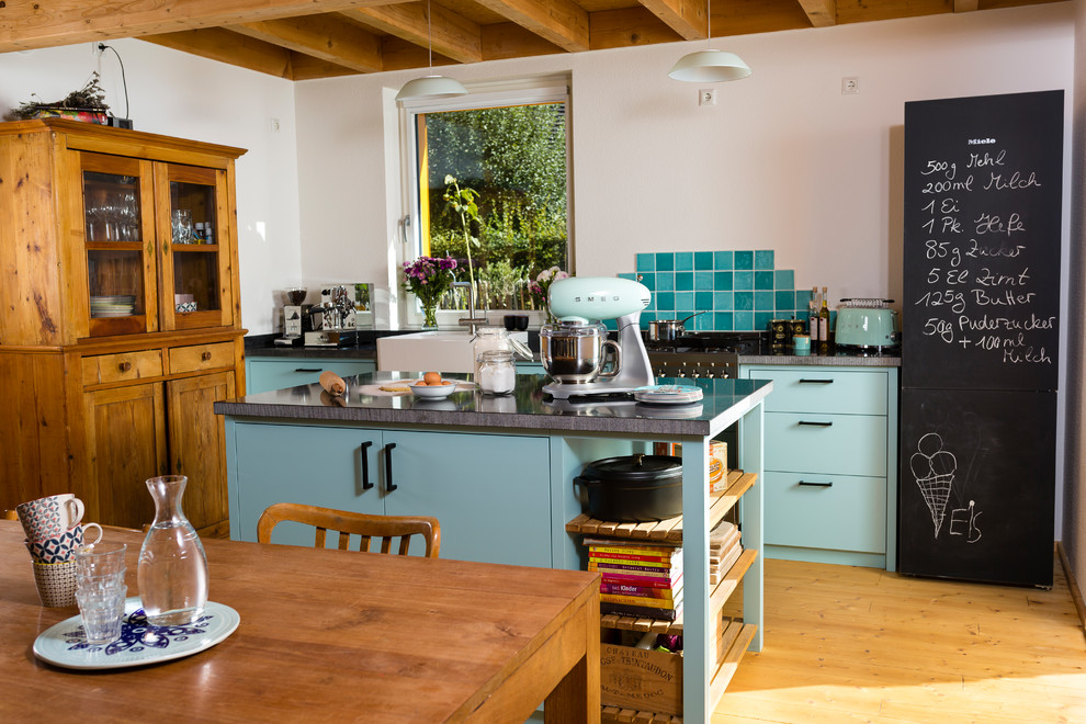 Exemple d'une cuisine ouverte parallèle romantique avec un évier posé, des portes de placard turquoises, une crédence blanche, une crédence en mosaïque, un sol en bois brun et îlot.