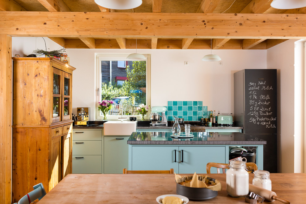 На фото: параллельная кухня-гостиная в стиле шебби-шик с накладной мойкой, бирюзовыми фасадами, белым фартуком, фартуком из плитки мозаики и островом