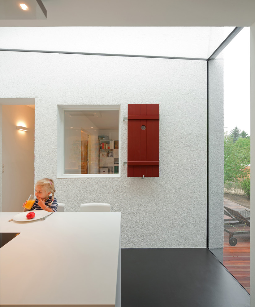 Idéer för ett mellanstort modernt kök med öppen planlösning, med vita skåp, vitt stänkskydd, en köksö och svart golv