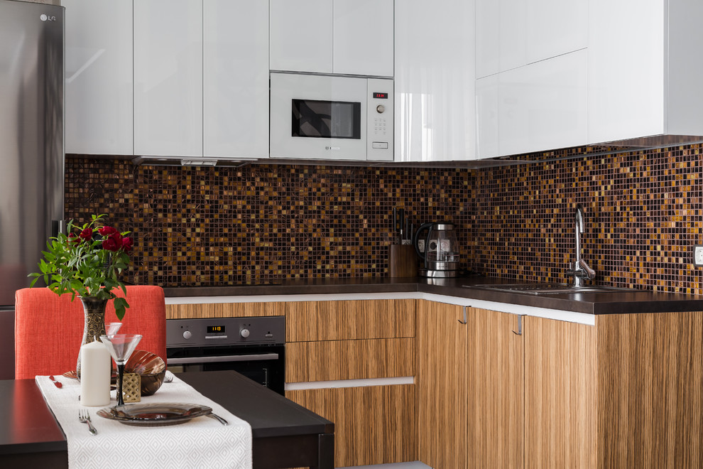 Inredning av ett modernt kök, med skåp i shakerstil, skåp i mellenmörkt trä, brunt stänkskydd, stänkskydd i mosaik och rostfria vitvaror