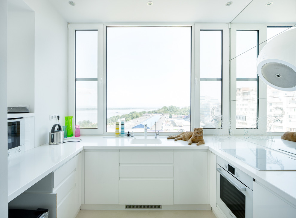Foto di una cucina design con ante lisce, ante bianche, nessuna isola, lavello integrato e elettrodomestici bianchi