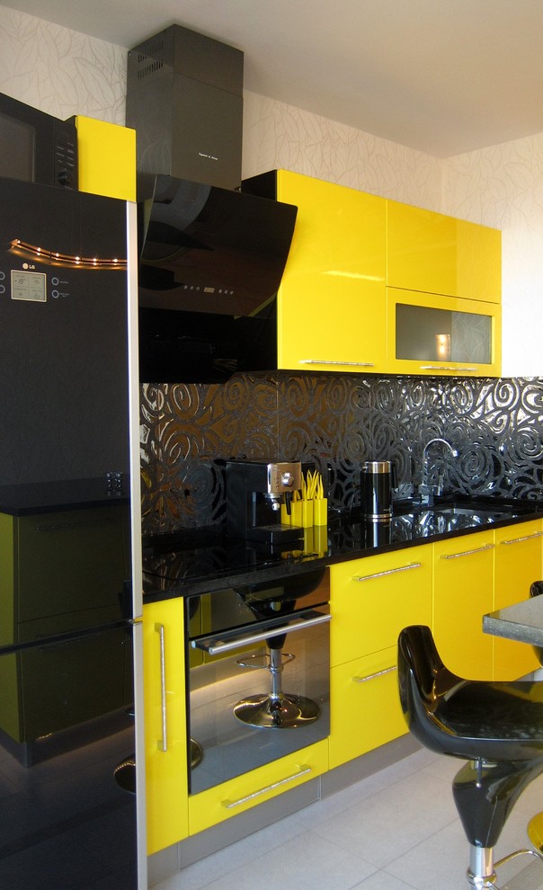 Inspiration for a small contemporary single-wall enclosed kitchen in Saint Petersburg with flat-panel cabinets, yellow cabinets, engineered stone countertops, black splashback, ceramic splashback, black appliances and an island.