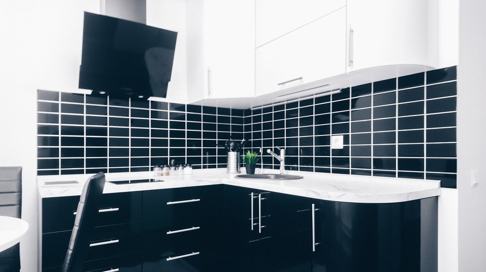 Diseño de cocina escandinava con fregadero bajoencimera, armarios con paneles lisos, puertas de armario blancas, salpicadero negro, electrodomésticos blancos y encimeras blancas