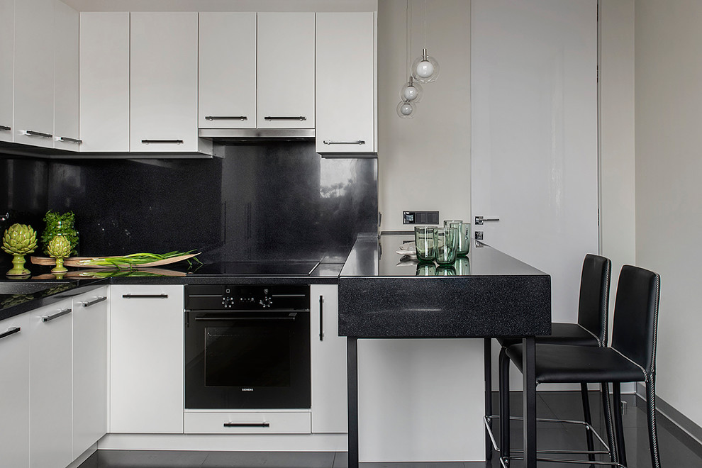 Inspiration for a contemporary u-shaped kitchen in Moscow with a submerged sink, flat-panel cabinets, white cabinets, black splashback, black appliances, a breakfast bar and black floors.