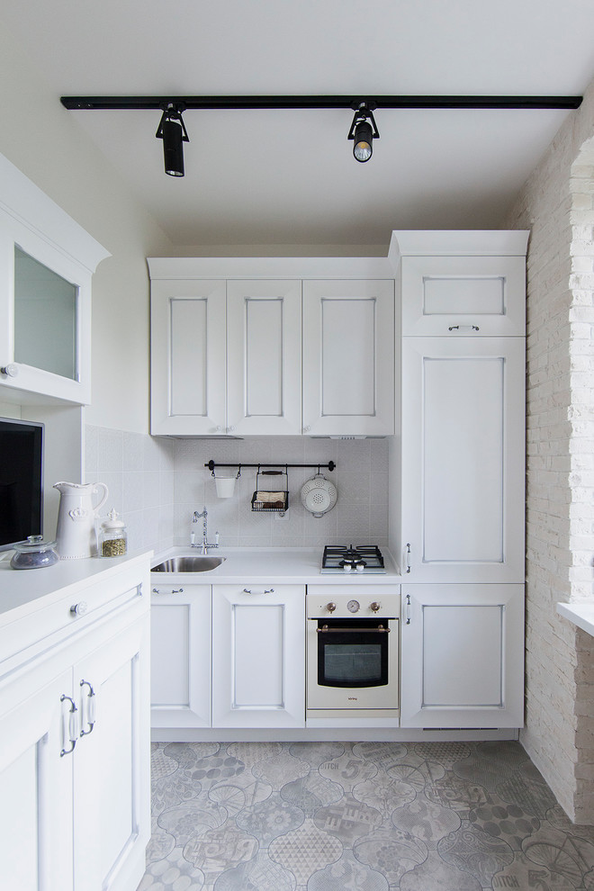 This is an example of a contemporary single-wall enclosed kitchen in Moscow with a submerged sink, recessed-panel cabinets, white cabinets, white splashback, white appliances, no island and grey floors.