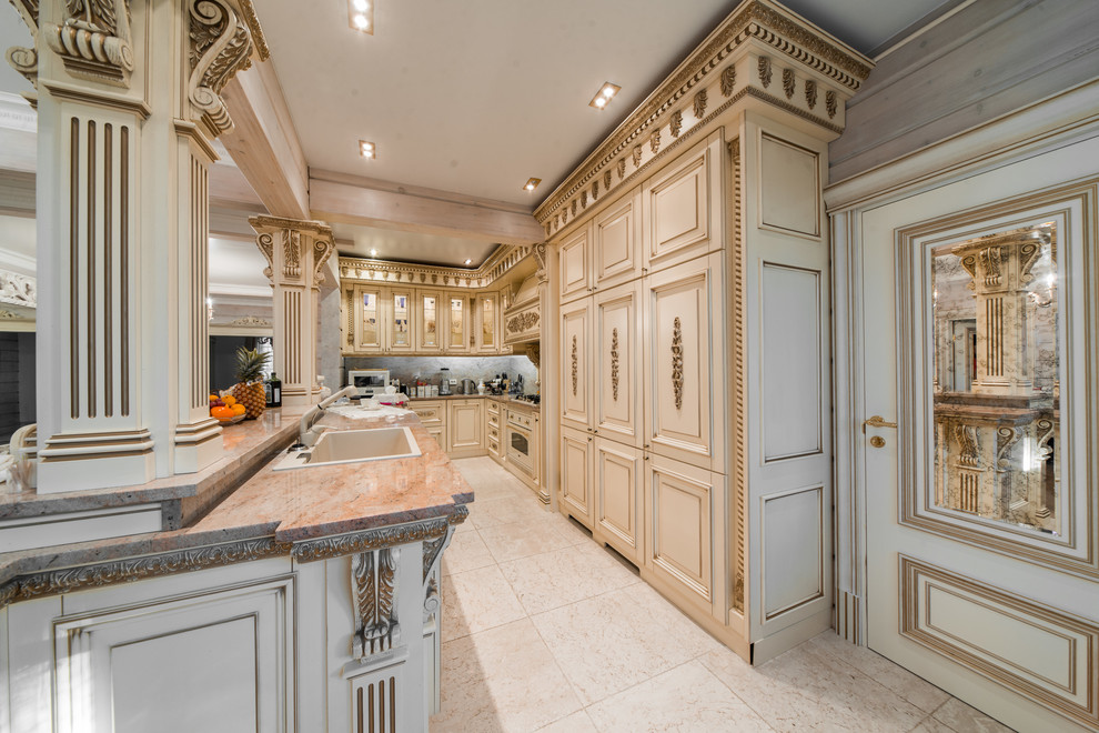 Foto de cocinas en L clásica grande abierta con una isla, fregadero encastrado, puertas de armario beige y electrodomésticos blancos