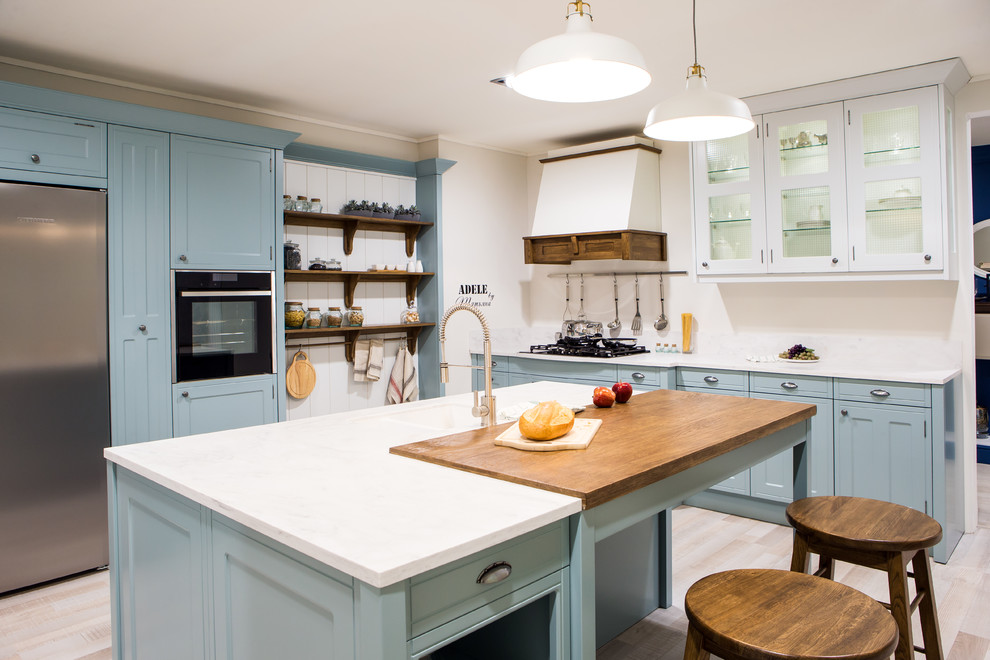 Inredning av ett medelhavsstil stort vit vitt kök, med en integrerad diskho, luckor med glaspanel, blå skåp, bänkskiva i koppar, vitt stänkskydd, rostfria vitvaror och en köksö