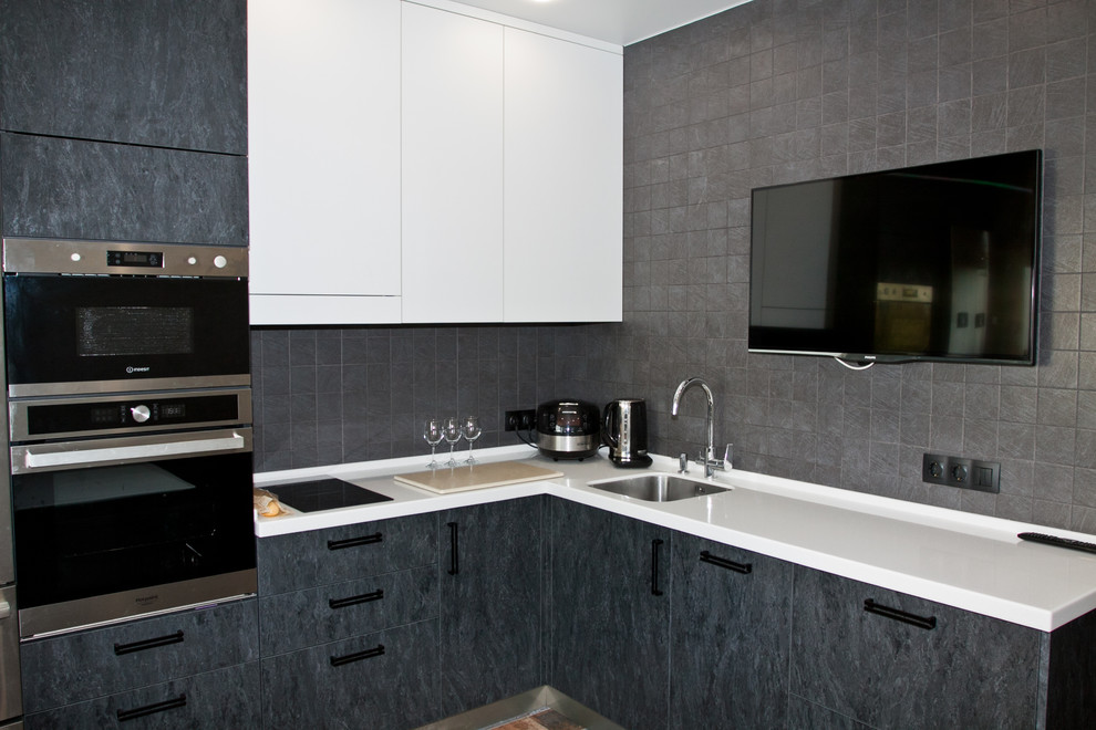 Photo of a medium sized contemporary l-shaped kitchen/diner in Moscow with a submerged sink, flat-panel cabinets, grey cabinets, composite countertops, grey splashback, porcelain splashback, stainless steel appliances, ceramic flooring, no island, multi-coloured floors and white worktops.