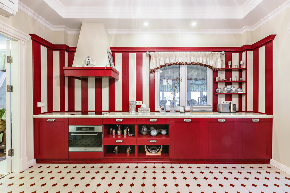 Cette image montre une cuisine linéaire traditionnelle fermée avec un placard avec porte à panneau encastré, des portes de placard rouges, une crédence multicolore, un électroménager en acier inoxydable, aucun îlot et un sol multicolore.