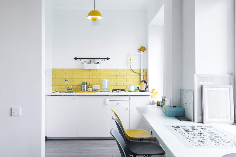Idéer för ett skandinaviskt linjärt kök, med en enkel diskho, släta luckor, vita skåp, gult stänkskydd, stänkskydd i tunnelbanekakel och mörkt trägolv