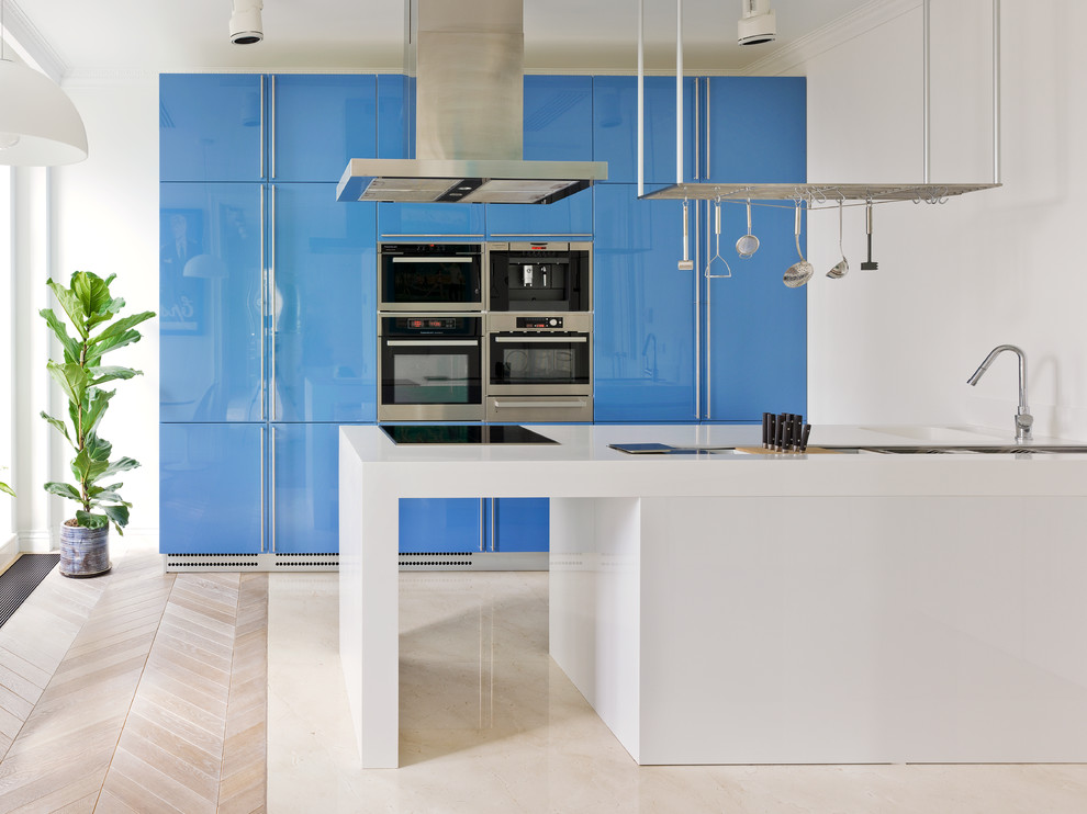 Inredning av ett modernt kök, med en integrerad diskho, släta luckor, blå skåp, rostfria vitvaror och en köksö
