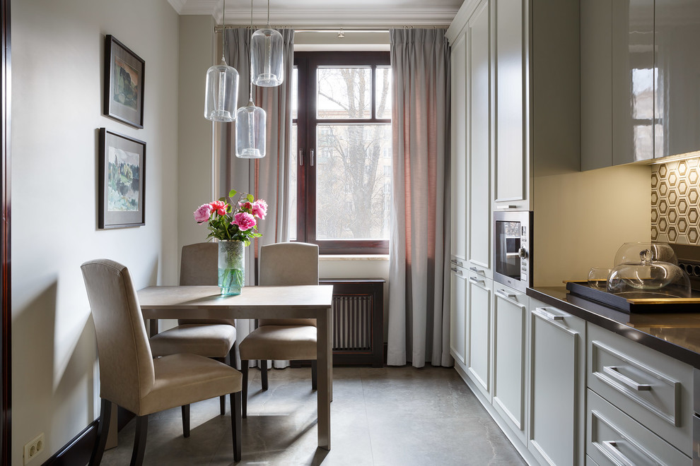 Ejemplo de cocina clásica renovada cerrada sin isla con puertas de armario blancas, electrodomésticos de acero inoxidable y suelo gris
