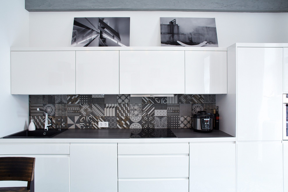 Exempel på ett industriellt linjärt kök med öppen planlösning, med släta luckor, vita skåp, grått stänkskydd och rostfria vitvaror