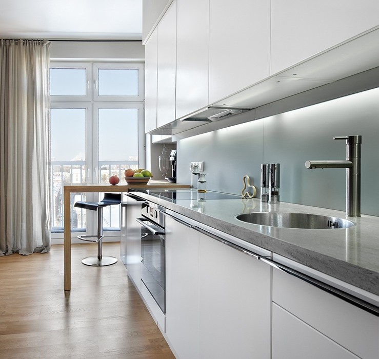 Immagine di una cucina minimal con lavello da incasso, ante lisce, ante bianche, paraspruzzi bianco, elettrodomestici in acciaio inossidabile e parquet chiaro
