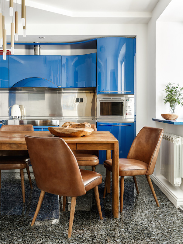 Imagen de cocina contemporánea con armarios con paneles lisos, puertas de armario azules, salpicadero metalizado, salpicadero de metal, electrodomésticos de acero inoxidable y suelo gris