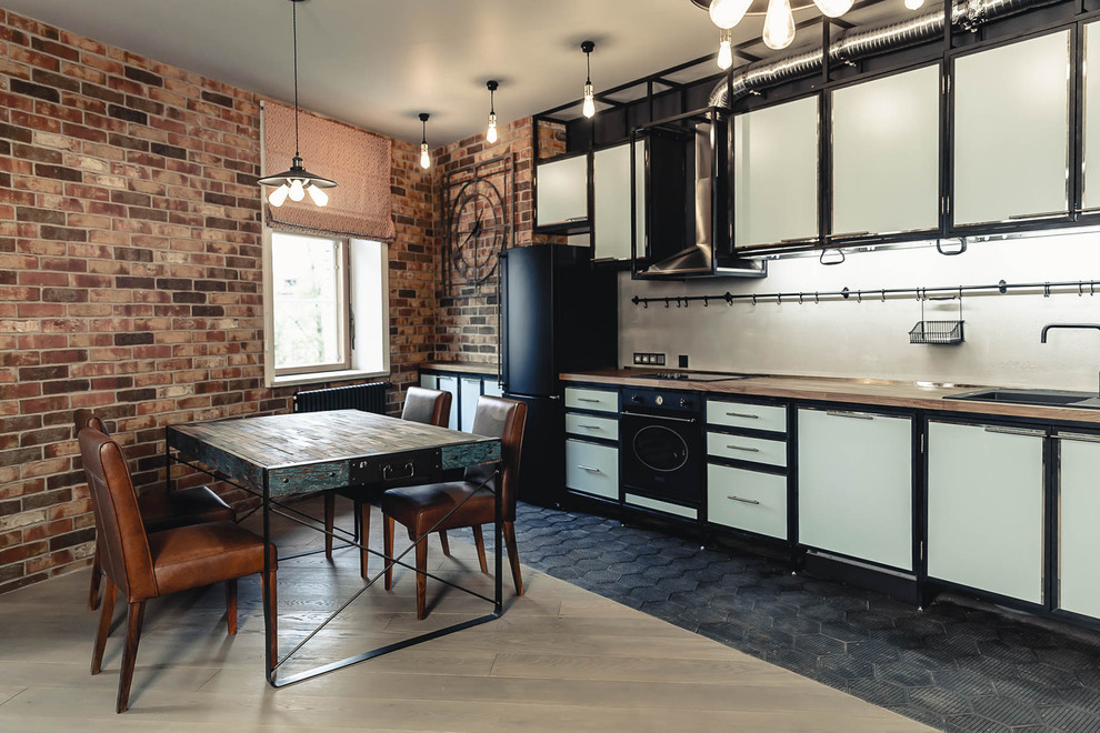 Стильный дизайн: прямая кухня-гостиная среднего размера в стиле лофт с накладной мойкой, плоскими фасадами, синими фасадами, деревянной столешницей, серым фартуком, черной техникой, черным полом и бежевой столешницей - последний тренд