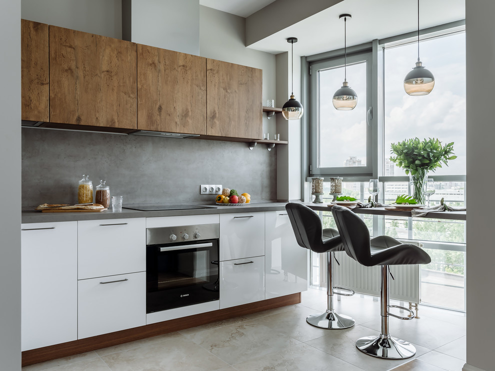 Immagine di una cucina lineare design con ante lisce, ante bianche, paraspruzzi grigio, elettrodomestici neri, pavimento beige e top grigio