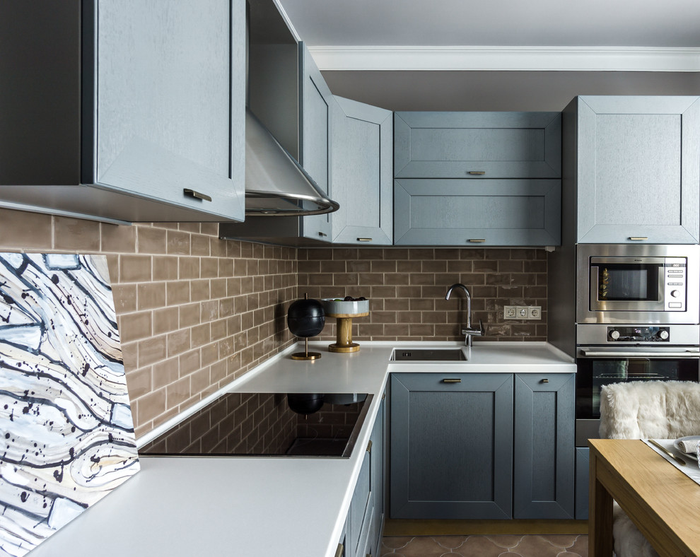 Klassisk inredning av ett kök, med en undermonterad diskho, grå skåp, brunt stänkskydd, rostfria vitvaror, brunt golv, skåp i shakerstil och stänkskydd i tunnelbanekakel