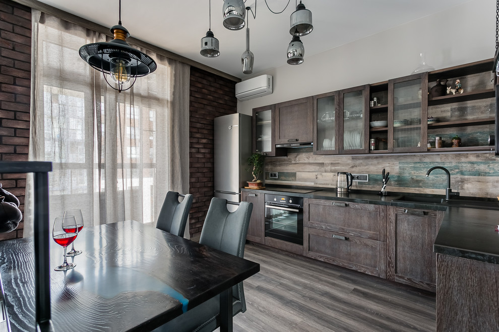 Urban l-shaped brown floor kitchen photo in Moscow with a drop-in sink, recessed-panel cabinets, dark wood cabinets, brown backsplash, black appliances, no island and black countertops