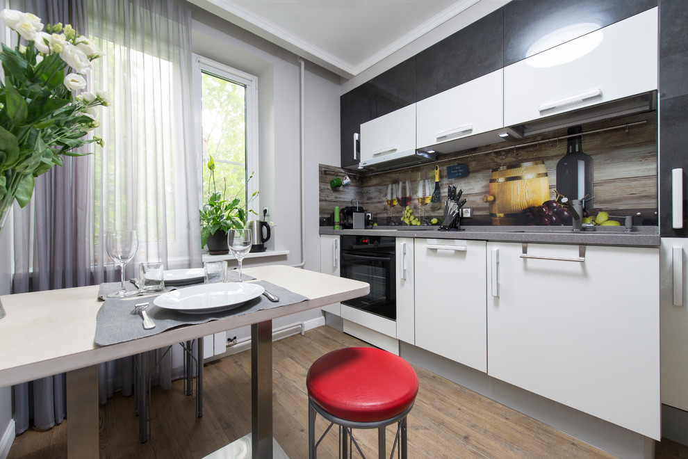 Esempio di una piccola cucina design con lavello integrato, ante lisce, ante bianche, top in superficie solida, paraspruzzi con lastra di vetro, elettrodomestici neri, pavimento in sughero, pavimento marrone e top grigio