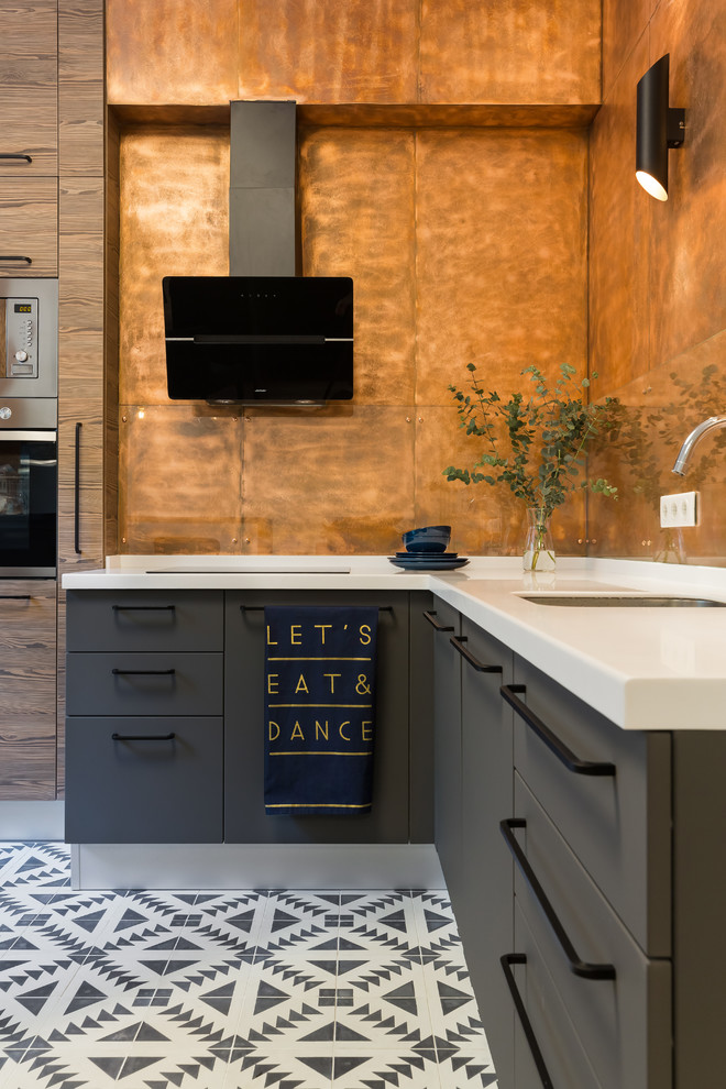 Modern inredning av ett mellanstort kök, med en undermonterad diskho, släta luckor, grå skåp, bänkskiva i koppar, glaspanel som stänkskydd, rostfria vitvaror, cementgolv, flerfärgat golv och orange stänkskydd