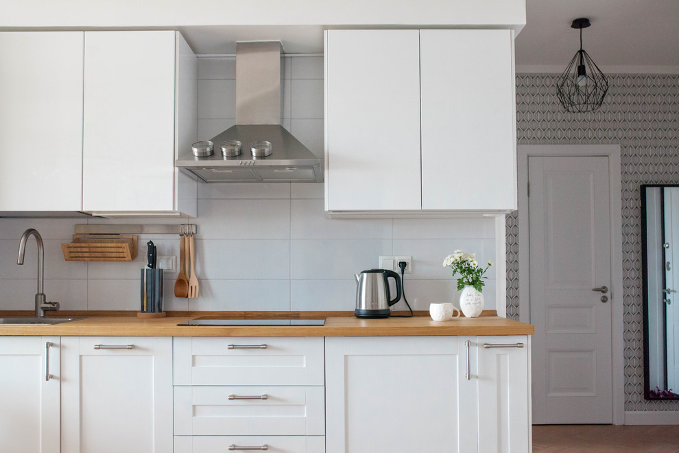 Inspiration pour une cuisine linéaire nordique de taille moyenne avec un évier posé, un placard à porte shaker, des portes de placard blanches et une crédence blanche.