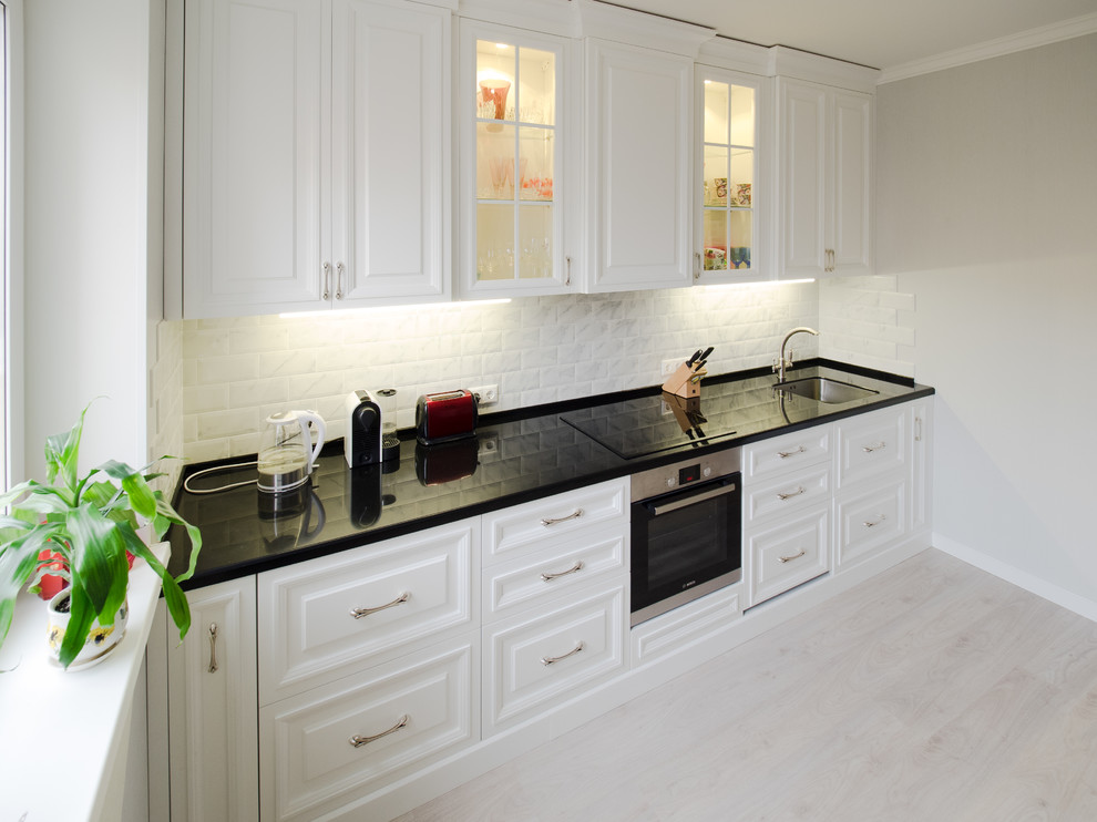 Medium sized classic single-wall kitchen/diner in Moscow with a submerged sink, white cabinets, composite countertops, grey splashback, metro tiled splashback, stainless steel appliances, laminate floors, no island and beige floors.