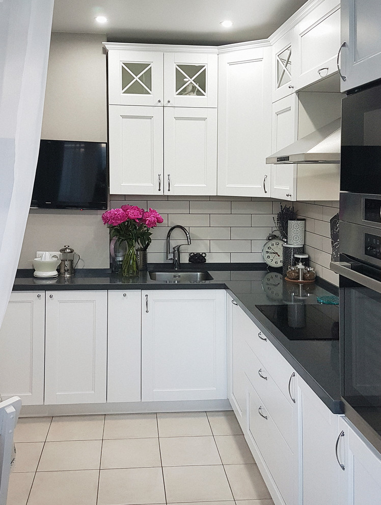 Photo of a medium sized traditional l-shaped enclosed kitchen in Moscow with a submerged sink, white cabinets, composite countertops, white splashback, stainless steel appliances, no island and shaker cabinets.