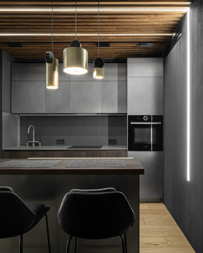 Foto på ett funkis grå kök, med en integrerad diskho, släta luckor, grå skåp, grått stänkskydd, en köksö och brunt golv
