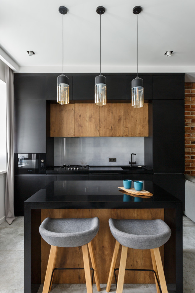Photo of an urban galley kitchen in Moscow with a submerged sink, flat-panel cabinets, black cabinets, grey splashback, black appliances, an island, grey floors and black worktops.