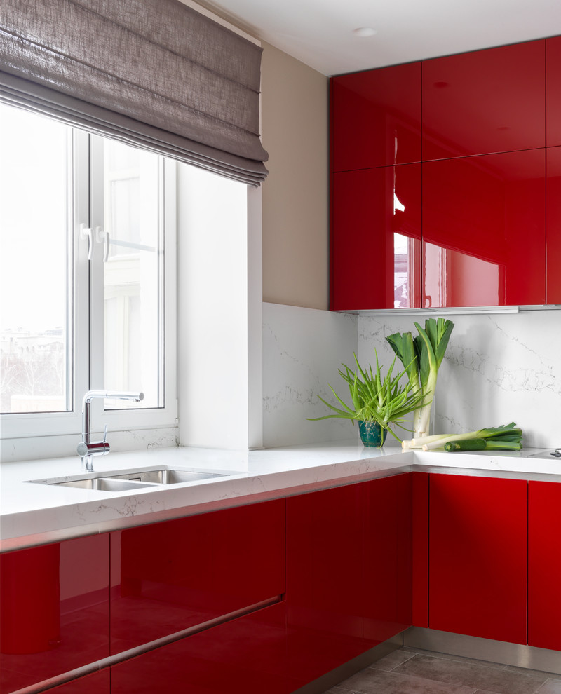 Idee per una cucina a L con lavello sottopiano, ante lisce, ante rosse, paraspruzzi bianco, pavimento grigio, top bianco e paraspruzzi a finestra