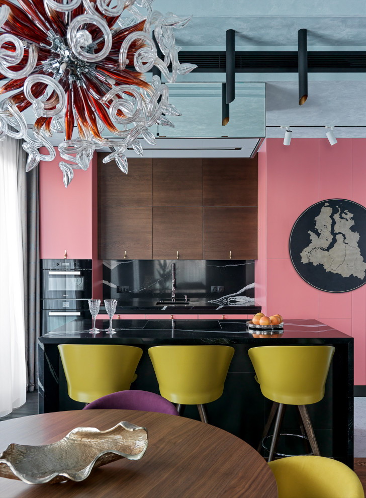 Пример оригинального дизайна: параллельная кухня в стиле фьюжн с обеденным столом, врезной мойкой, плоскими фасадами, розовыми фасадами, черным фартуком, фартуком из каменной плиты, черной техникой, островом, белым полом и черной столешницей